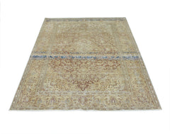 A vintage Persian Kerman rug featuring a central medallion and intricate floral patterns in tan.