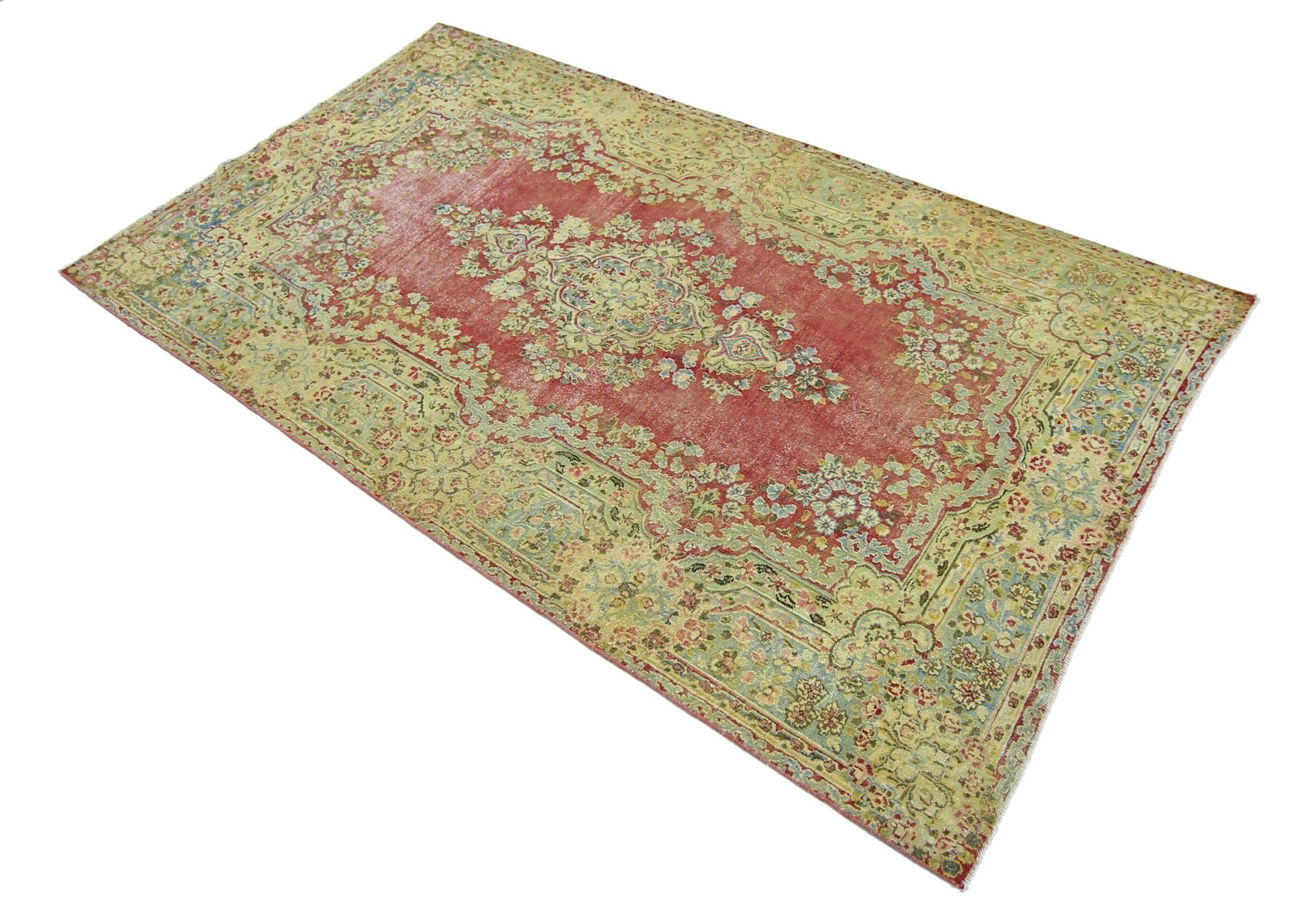 A vintage Persian Kerman rug featuring a central floral medallion on a faded red field.