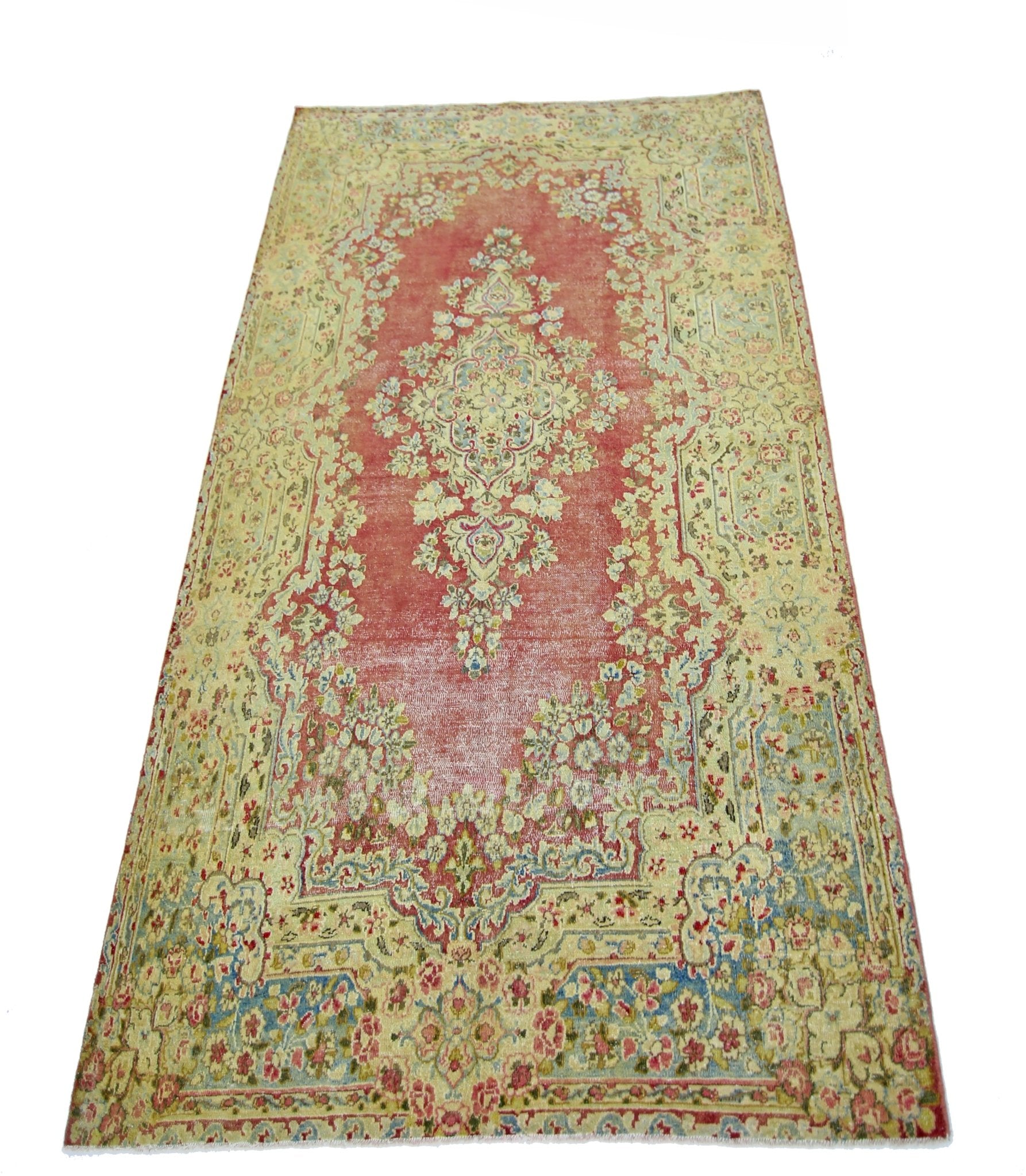 A vintage Persian Kerman rug featuring a central floral medallion on a faded red field.