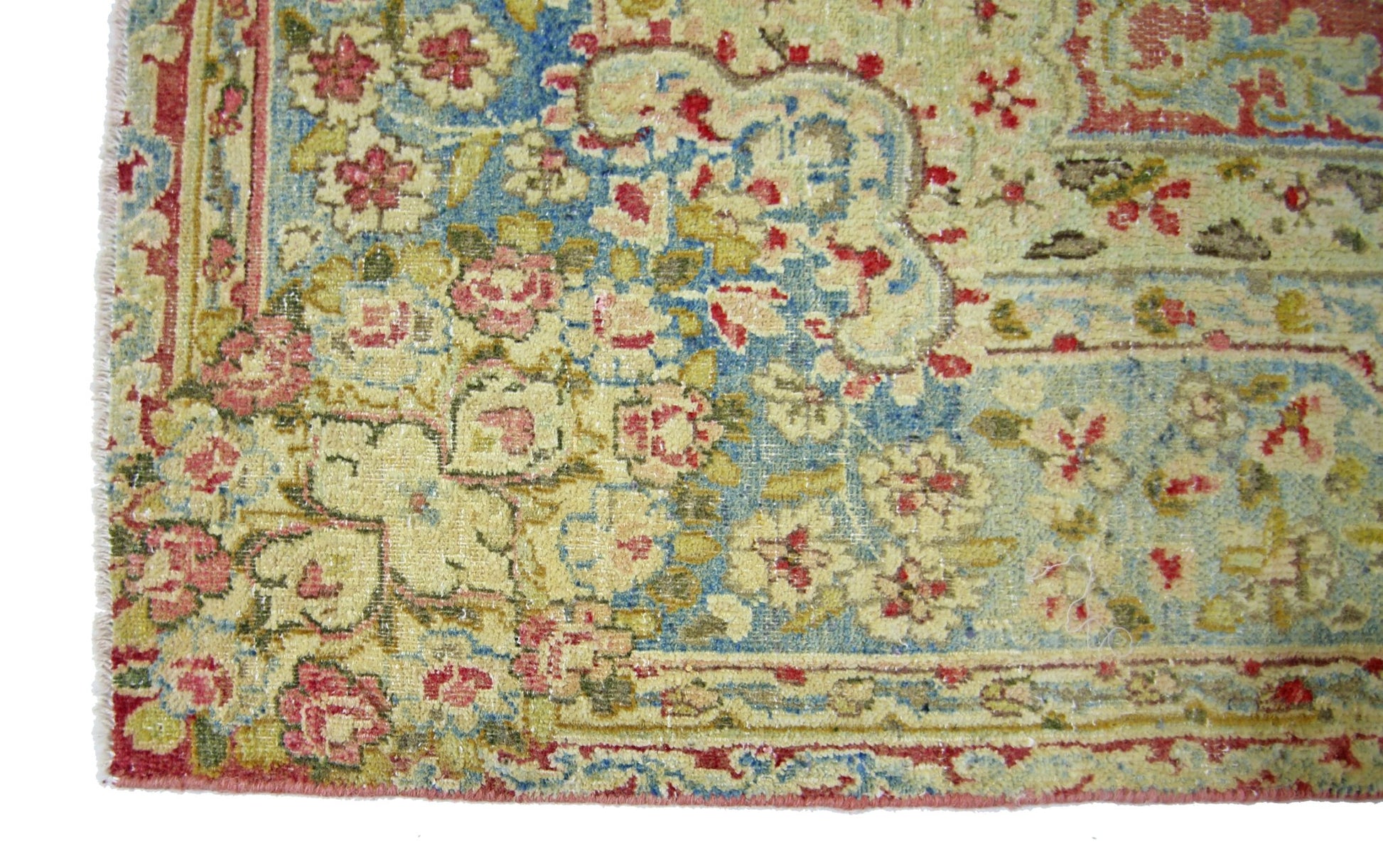 A vintage Persian Kerman rug featuring an intricate floral pattern in soft blue and cream tones.