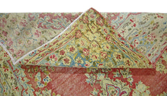 A vintage Persian Kerman rug with a folded corner revealing a floral pattern in red, blue, and gold.