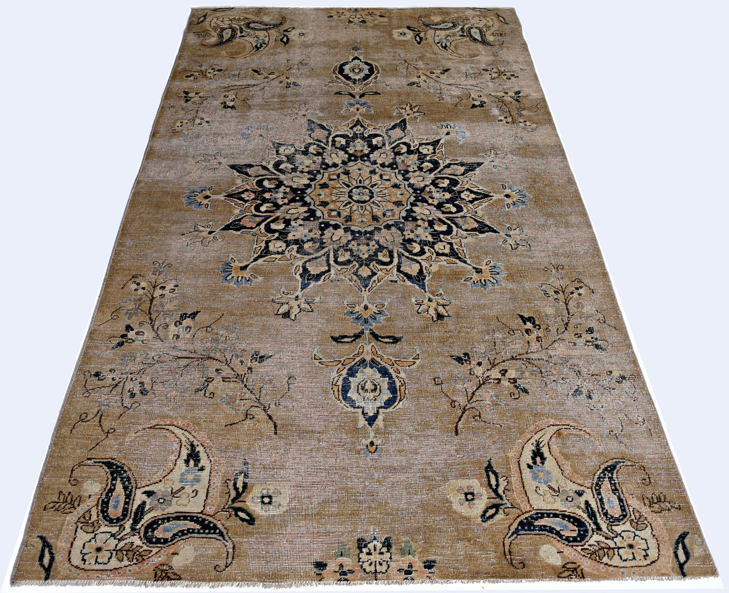 A vintage Persian Kerman rug featuring a central medallion and intricate floral motifs in tan.