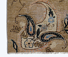 A close-up of a vintage Persian Kerman rug featuring intricate floral and paisley motifs.