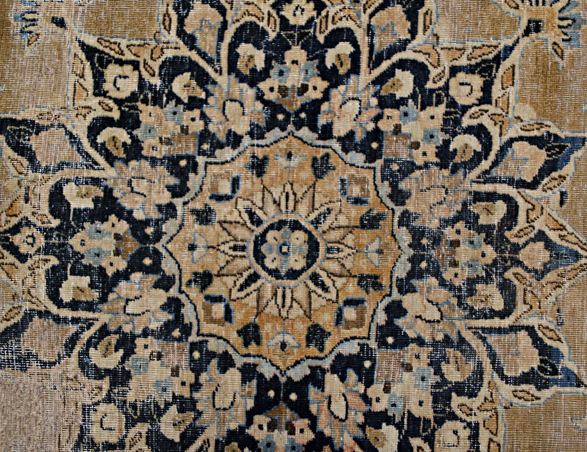 A vintage Persian Kerman rug featuring an intricate floral medallion in tan and navy blue.