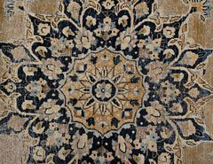 A vintage Persian Kerman rug featuring an intricate floral medallion in tan and navy blue.