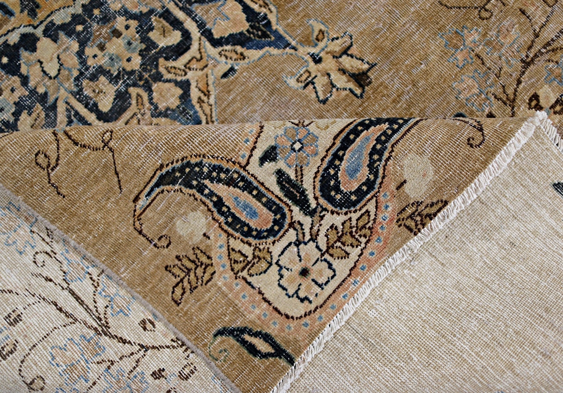A vintage Persian Kerman rug featuring a tan field with intricate blue and floral paisley patterns.