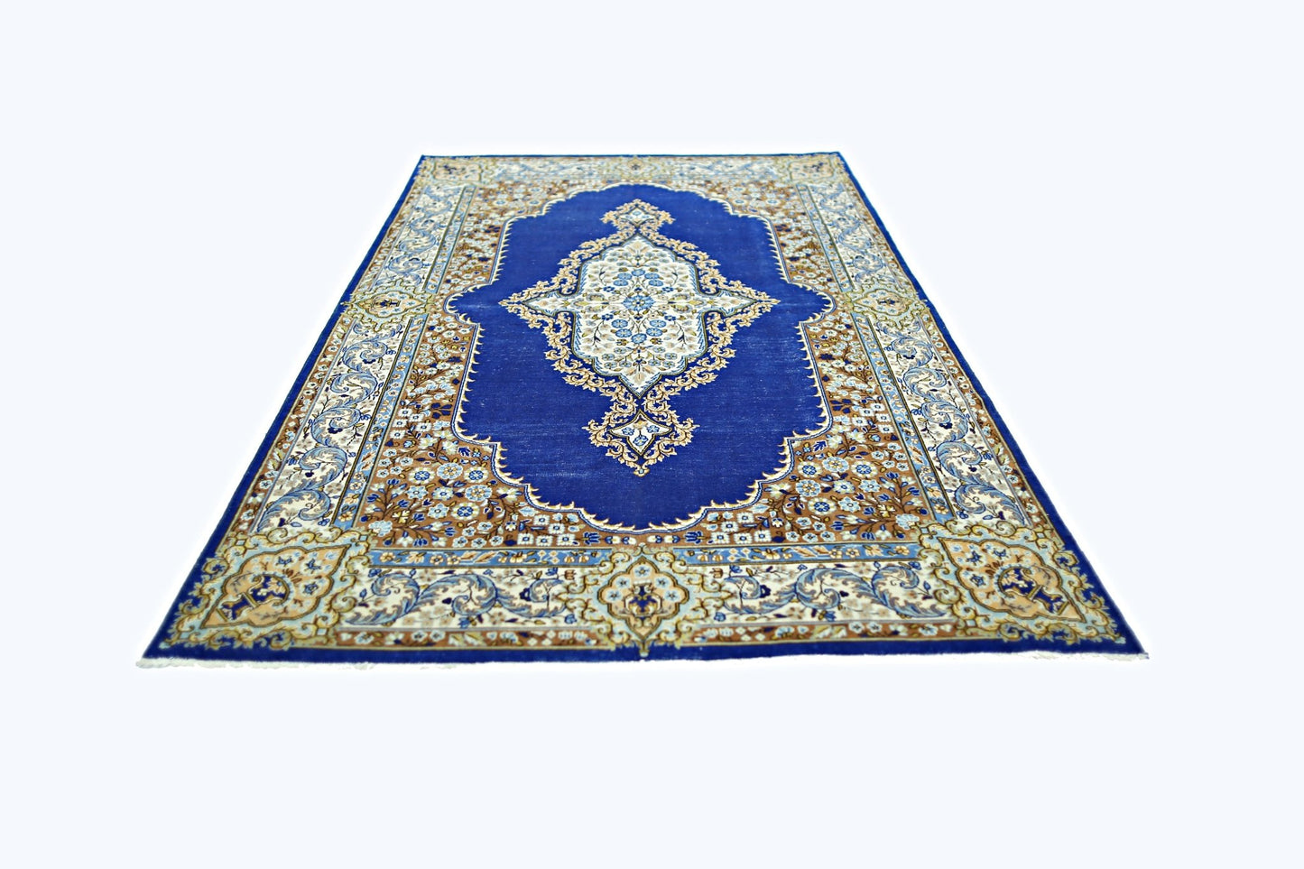 A vintage Persian Kerman rug featuring a central floral medallion on a deep blue field.