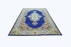 A vintage Persian Kerman rug featuring a central floral medallion on a deep blue field.