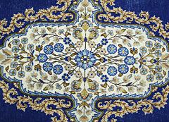 A vintage Persian Kerman rug featuring an intricate floral medallion on a deep blue background.