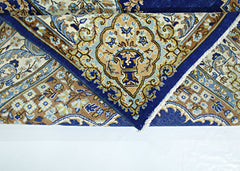A vintage Persian Kerman rug featuring a blue and tan floral medallion pattern.