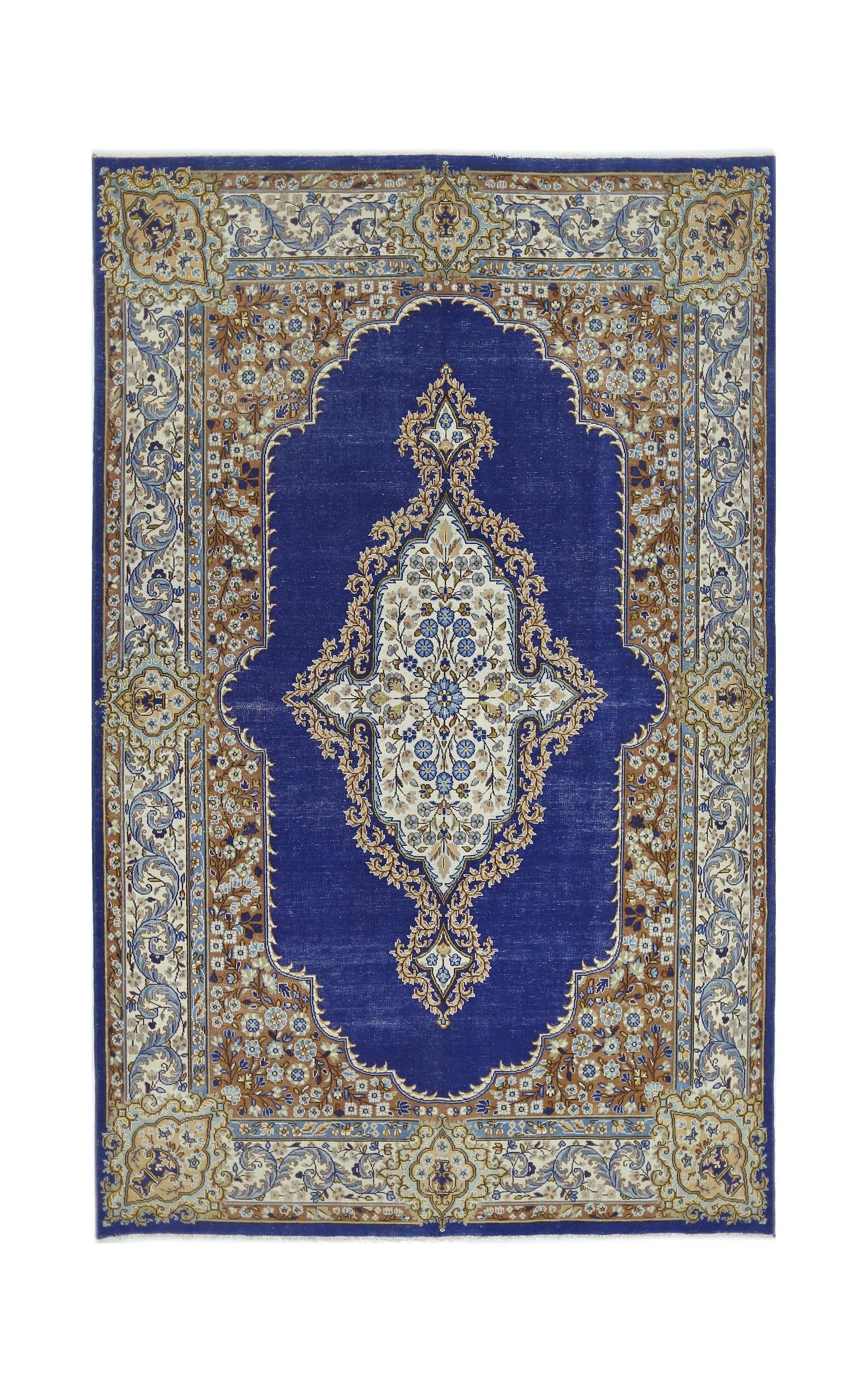 A vintage Persian Kerman rug featuring a central floral medallion on a deep blue field.