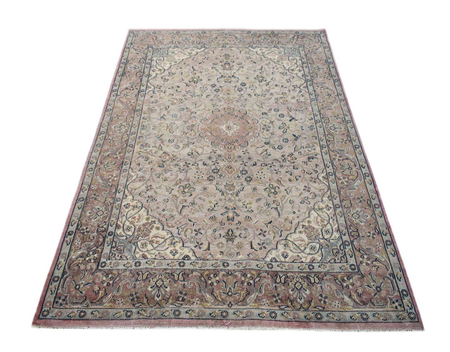 A vintage Persian Kerman rug featuring a central medallion and intricate floral patterns in pink.