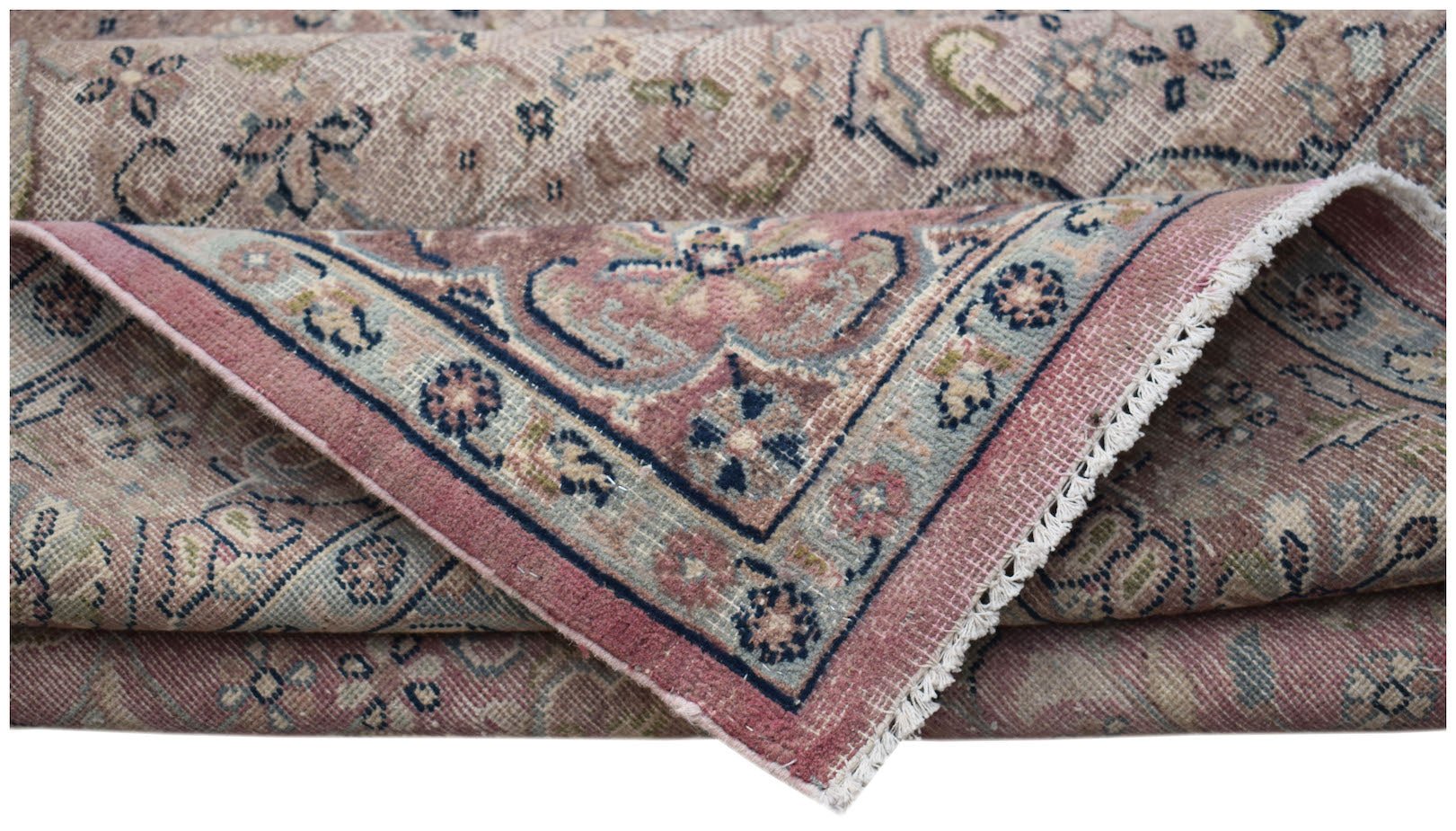A folded vintage Persian Kerman rug featuring a floral medallion design in muted pink and blue.
