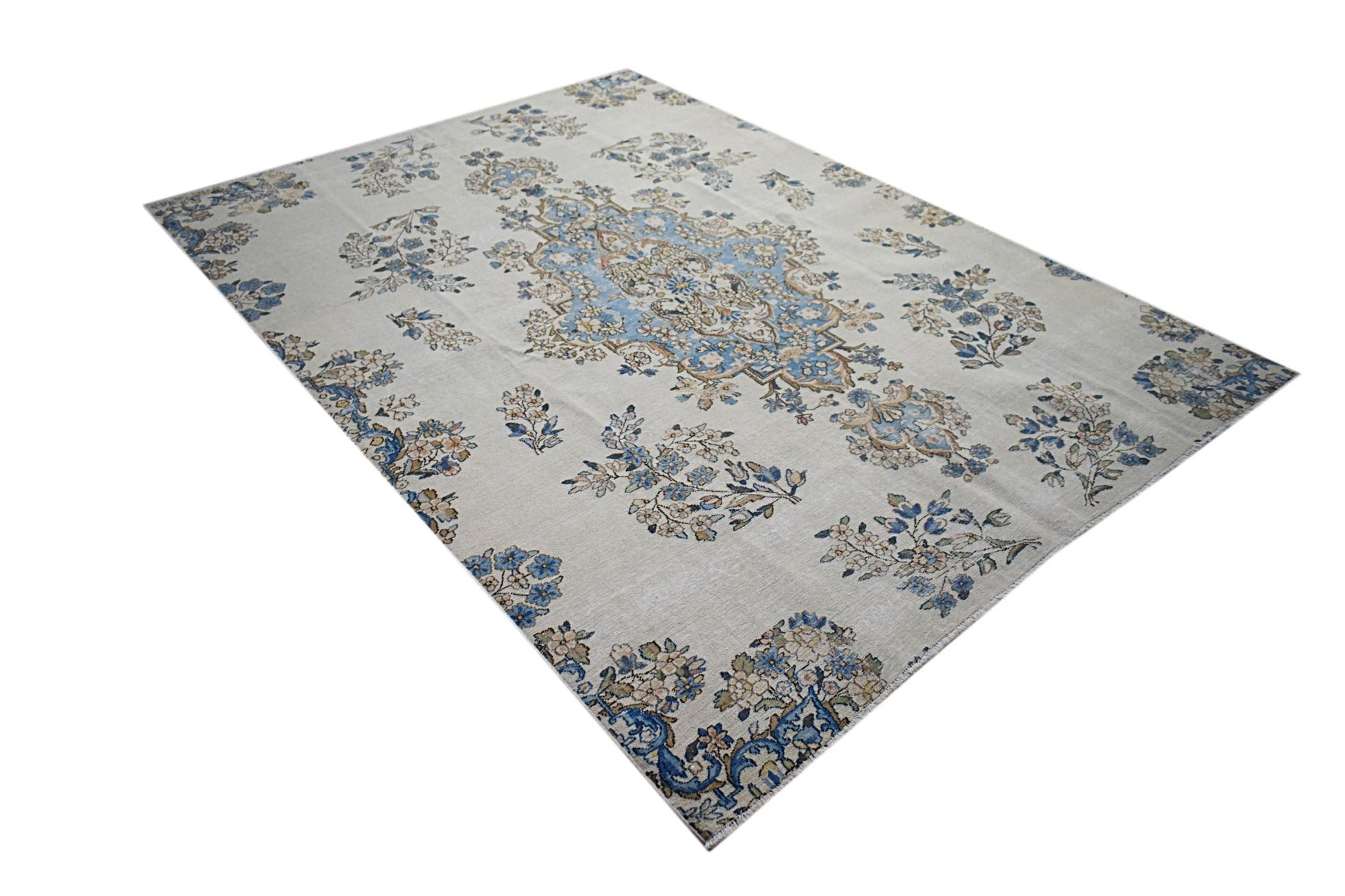 A vintage Persian Kerman rug featuring a central medallion and intricate floral patterns.