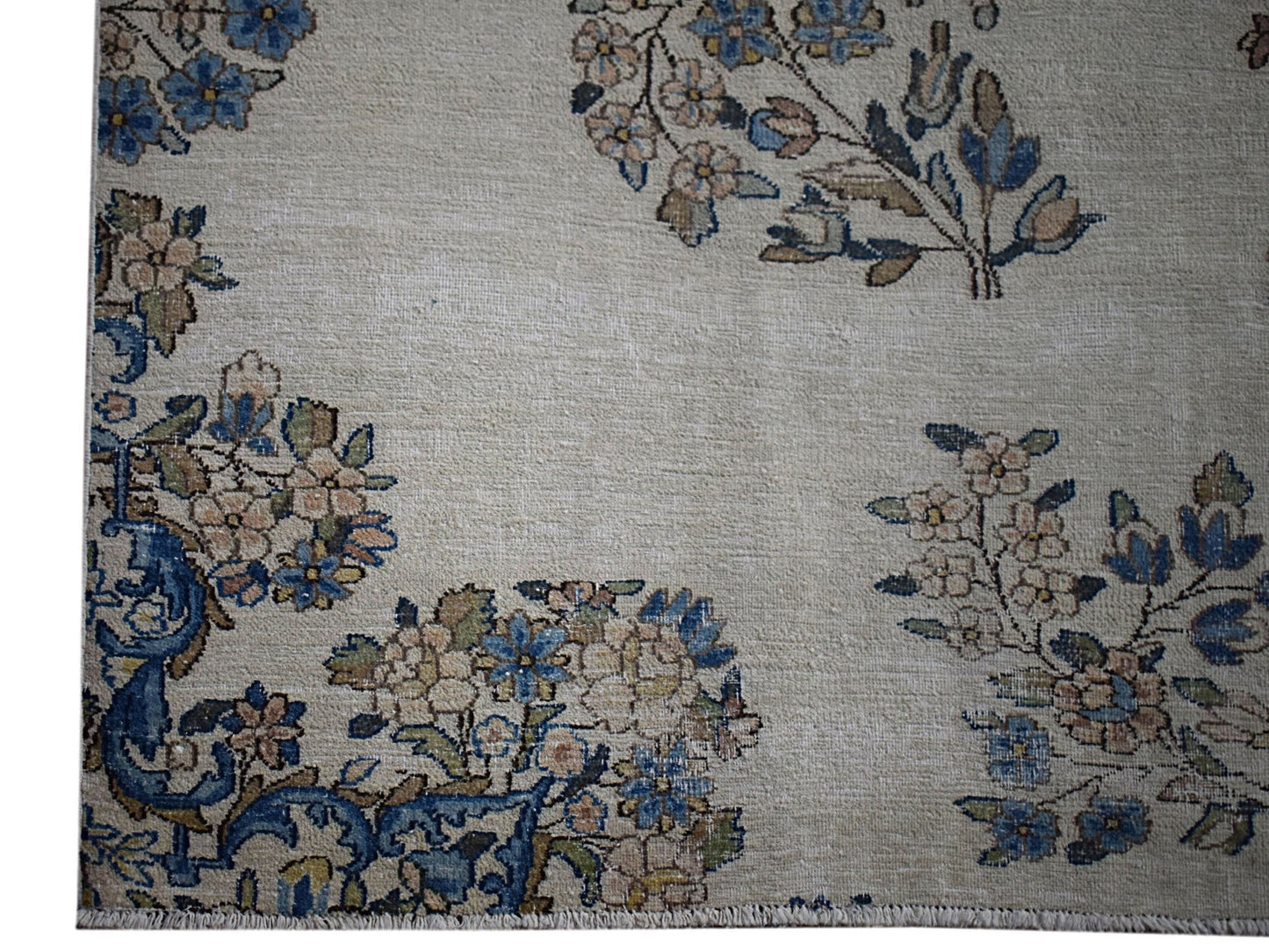 A vintage Persian Kerman rug featuring intricate floral motifs in blue and beige tones.