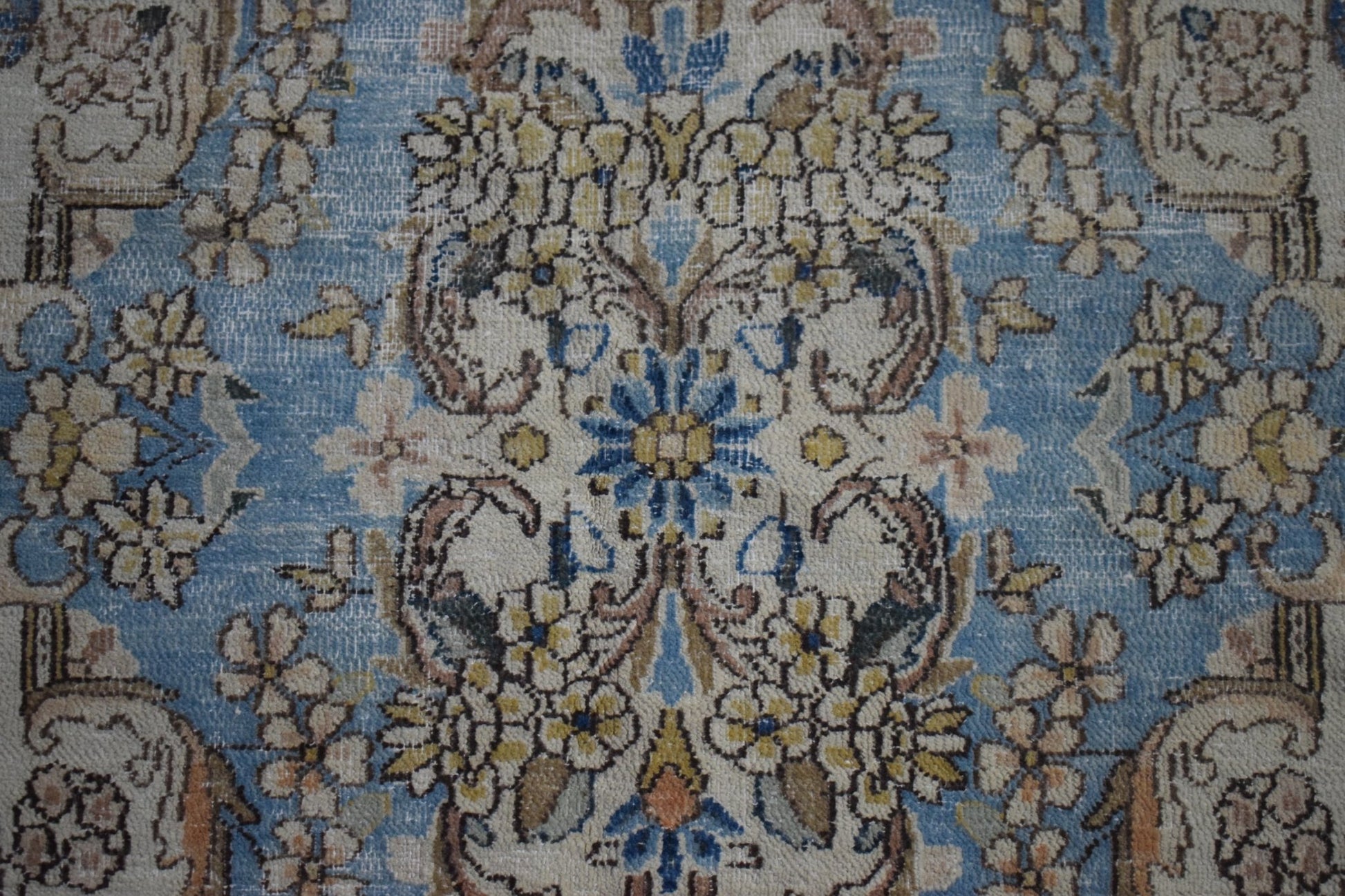 A vintage Persian Kerman rug featuring an intricate floral medallion pattern in blue and cream.