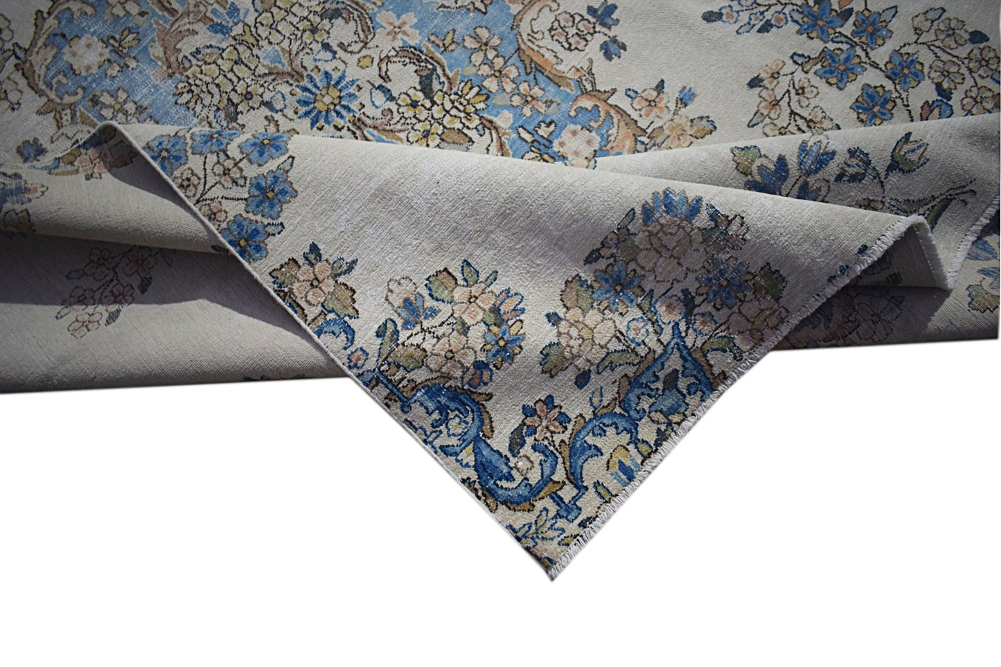 A vintage Persian Kerman rug featuring intricate floral patterns in blue and cream tones.