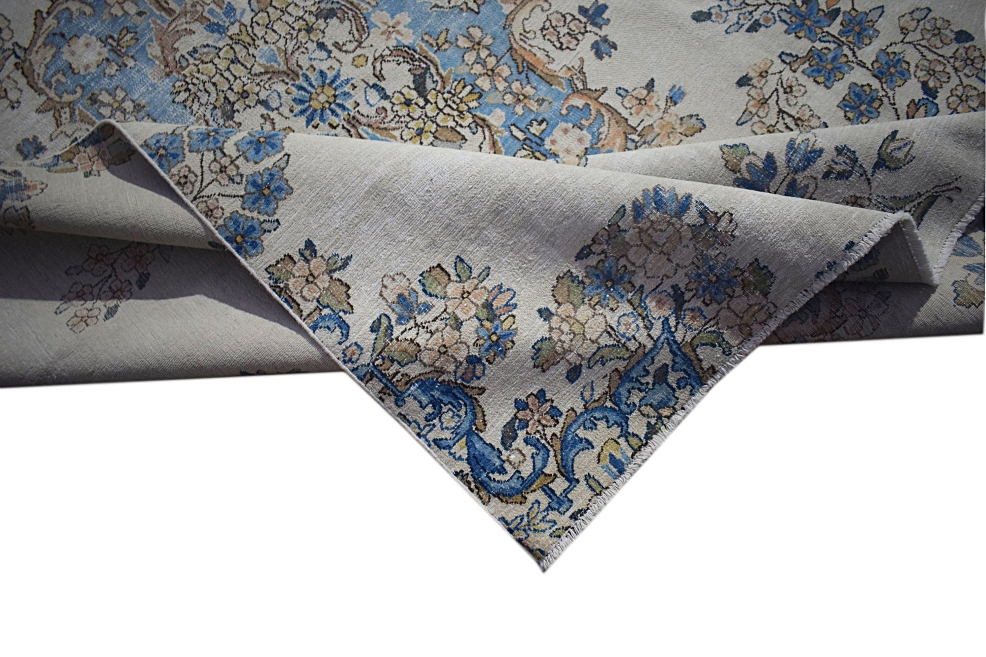 A vintage Persian Kerman rug featuring intricate floral patterns in blue and cream tones.