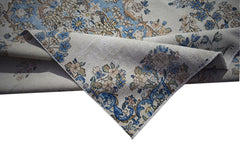 A vintage Persian Kerman rug featuring intricate floral patterns in blue and cream tones.