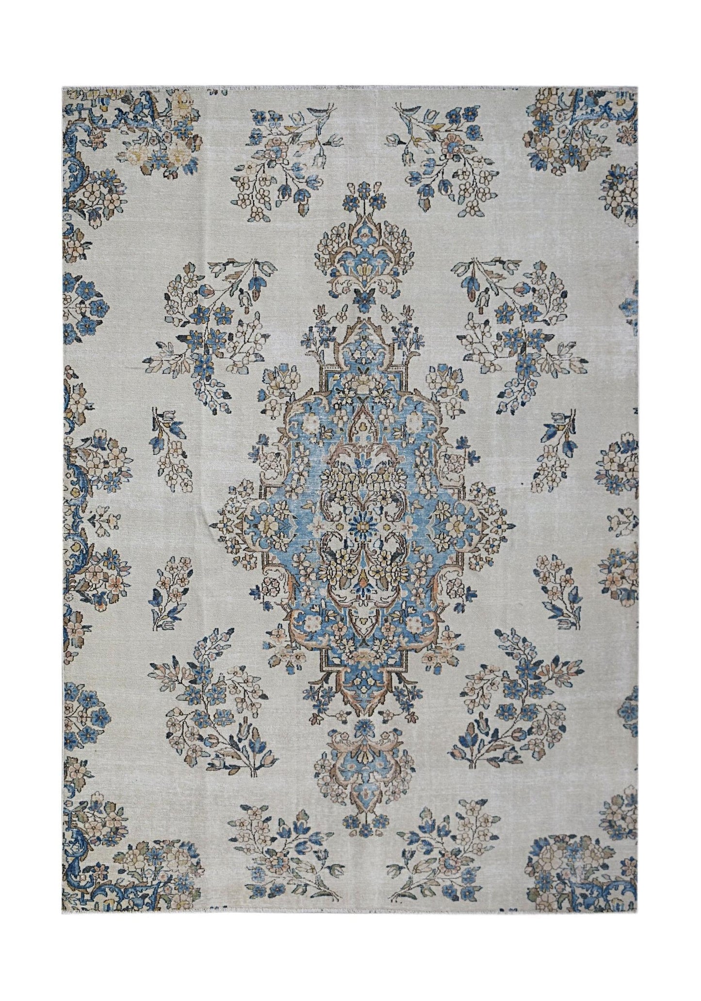 A vintage Persian Kerman rug featuring a central blue floral medallion on a light cream field.