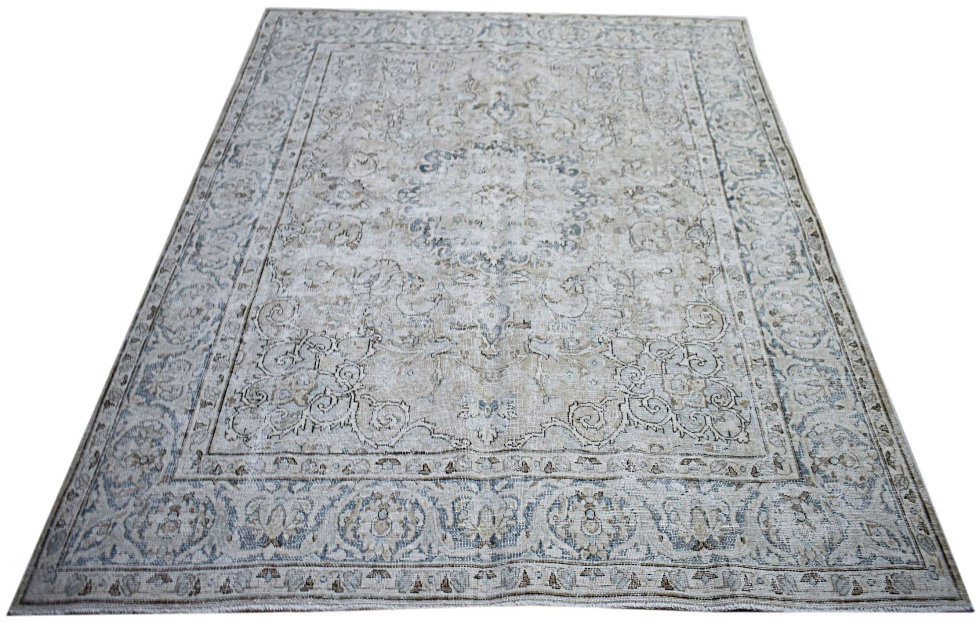 A vintage Persian Kerman rug featuring a central medallion and intricate floral patterns in blue.