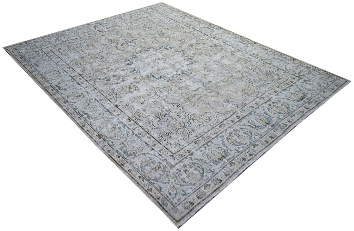 A vintage Persian Kerman rug featuring a central medallion and intricate floral patterns in blue.