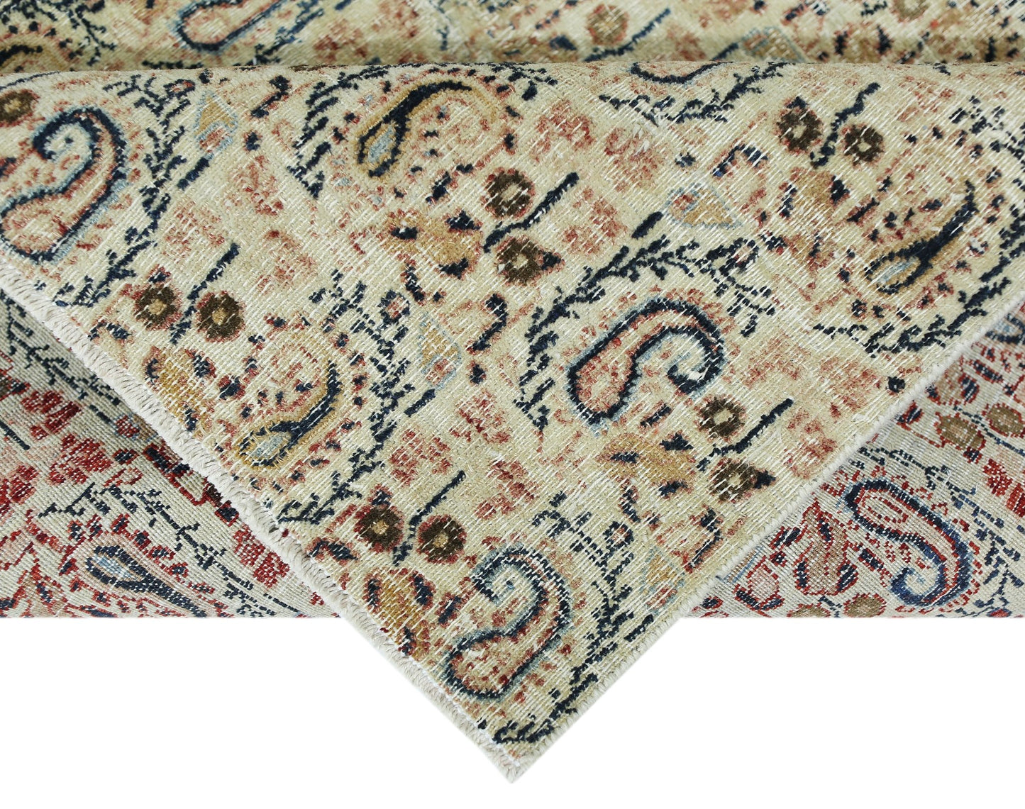 A vintage Turkish rug with a distressed paisley pattern in muted red, blue, and beige tones.