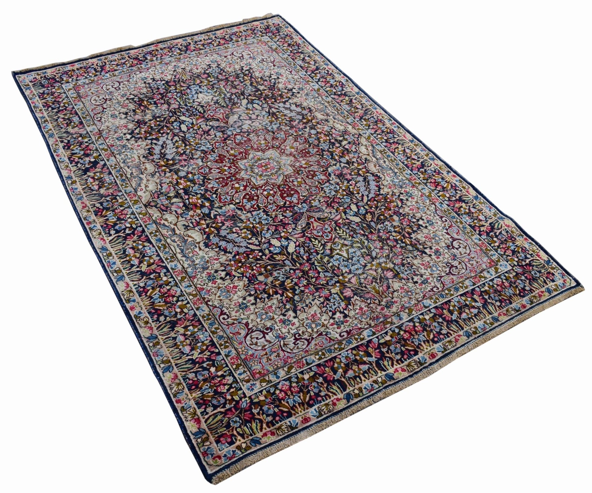 A vintage Persian Kerman rug featuring an intricate floral medallion design in deep blue and red.