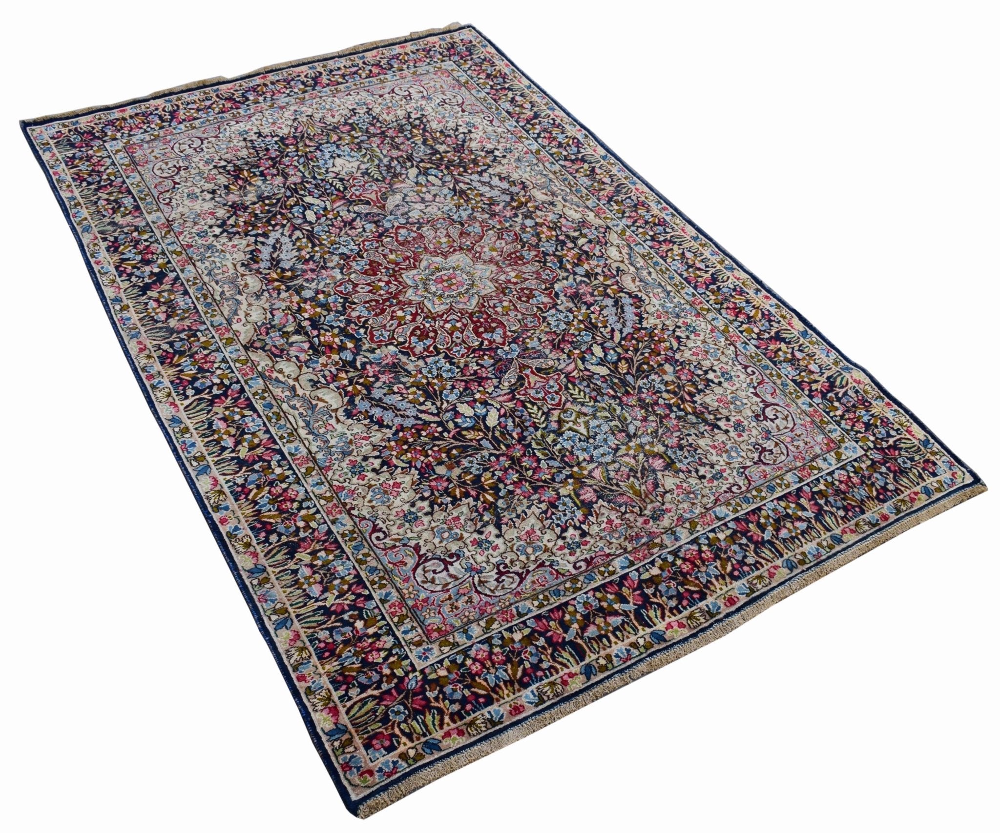 A vintage Persian Kerman rug featuring an intricate floral medallion design in deep blue and red.