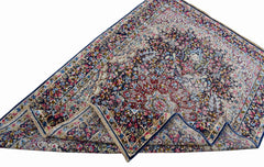 A vintage Persian Kerman rug featuring an intricate floral medallion design in blue and red tones.