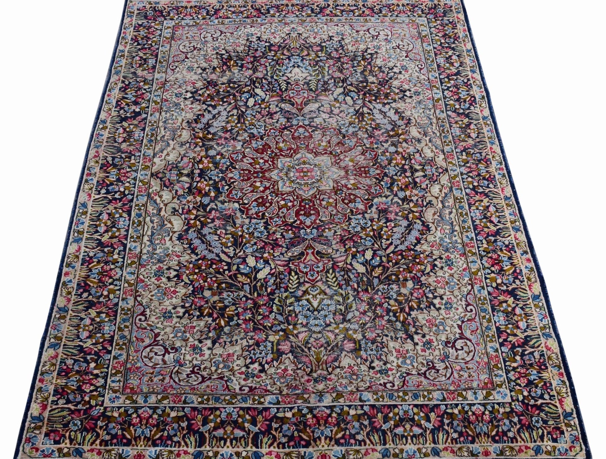A vintage Persian Kerman rug featuring an intricate floral medallion design in soft, muted tones.