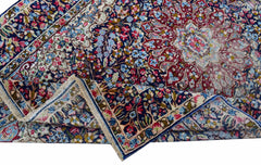 A vintage Persian Kerman rug featuring an intricate floral medallion design in blue and red.