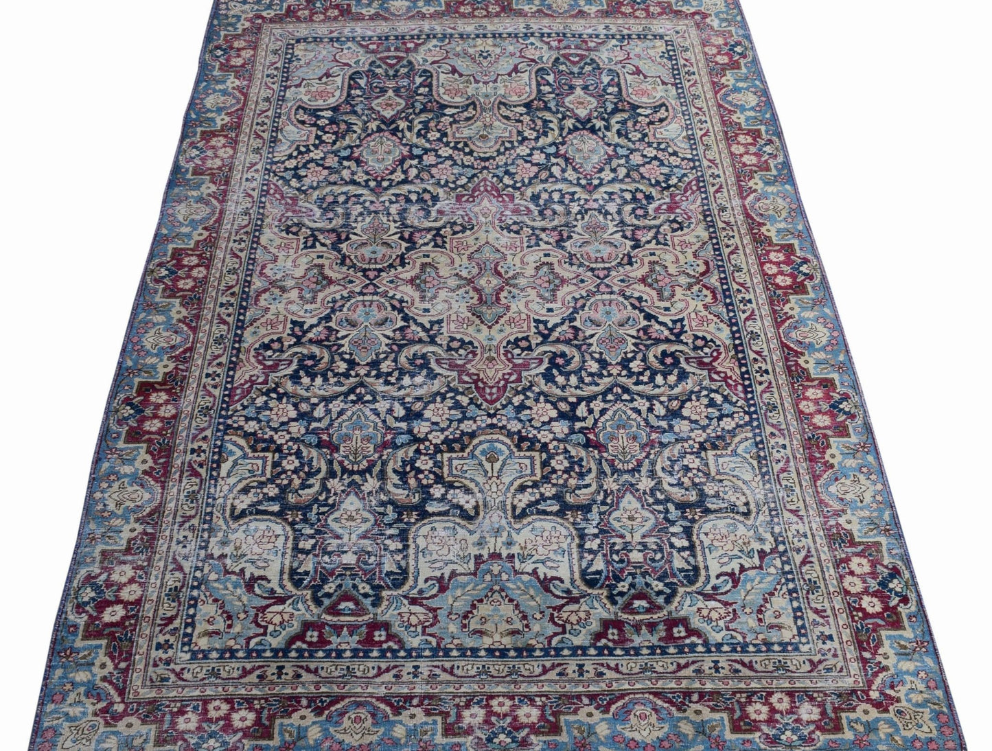A vintage Persian Kerman rug featuring an intricate floral medallion design in blue and red tones.