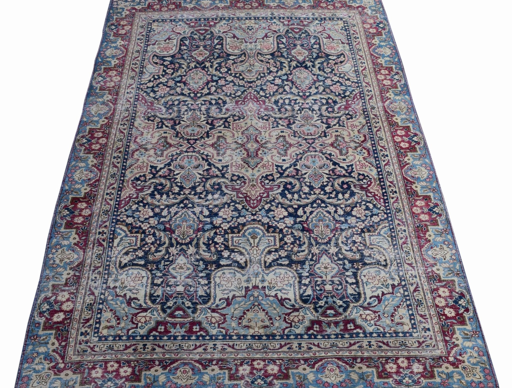 A vintage Persian Kerman rug featuring an intricate floral medallion design in blue and red tones.