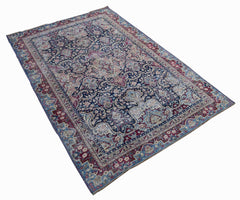 A vintage Persian Kerman rug featuring an intricate floral medallion design in blue and red tones.