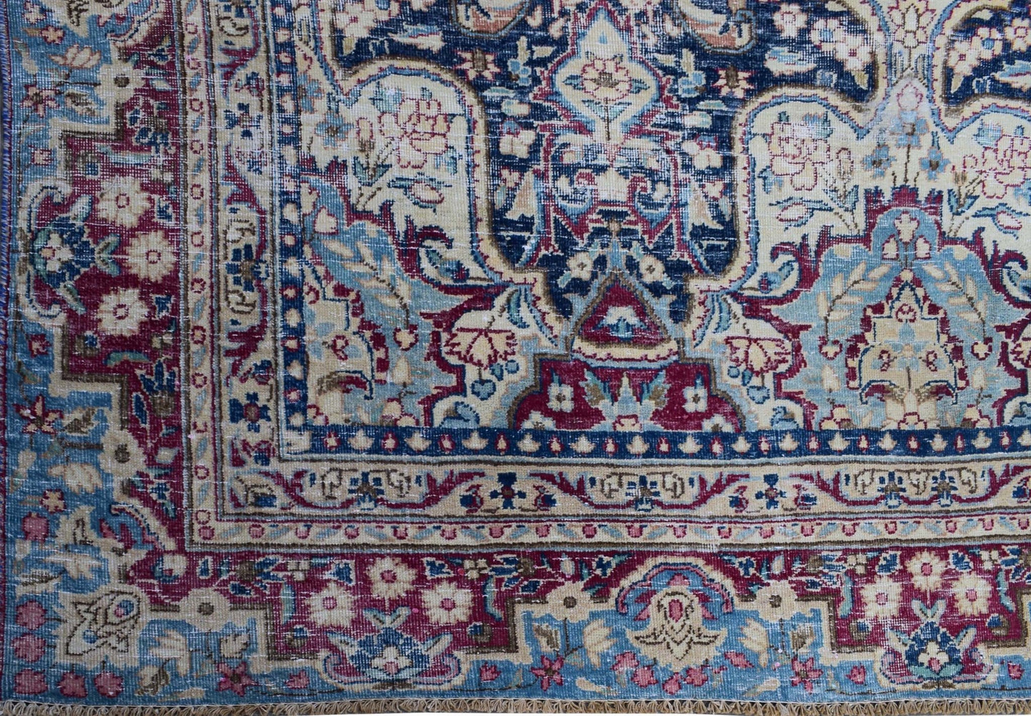 A vintage Persian Kerman rug featuring an intricate floral medallion design in blue and red tones.