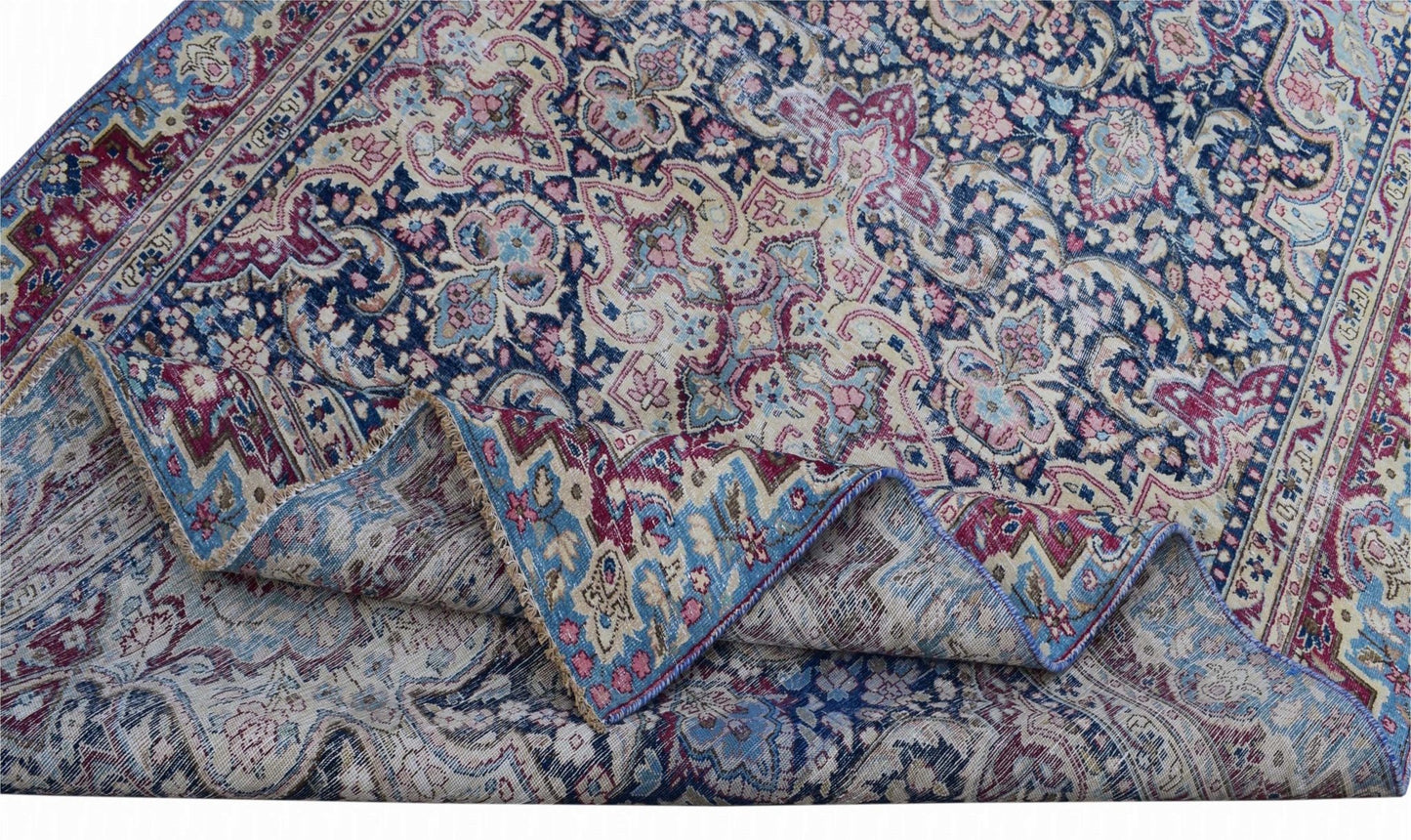 A vintage Persian Kerman rug featuring an intricate floral medallion pattern in blue and pink.