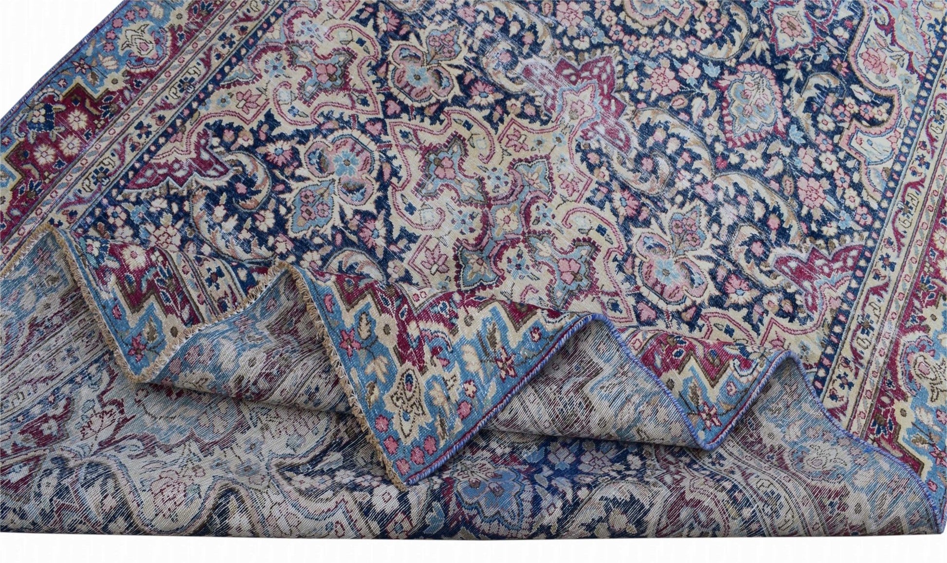 A vintage Persian Kerman rug featuring an intricate floral medallion pattern in blue and pink.