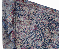 A vintage Persian Kerman rug featuring an intricate floral medallion pattern in blue and pink.