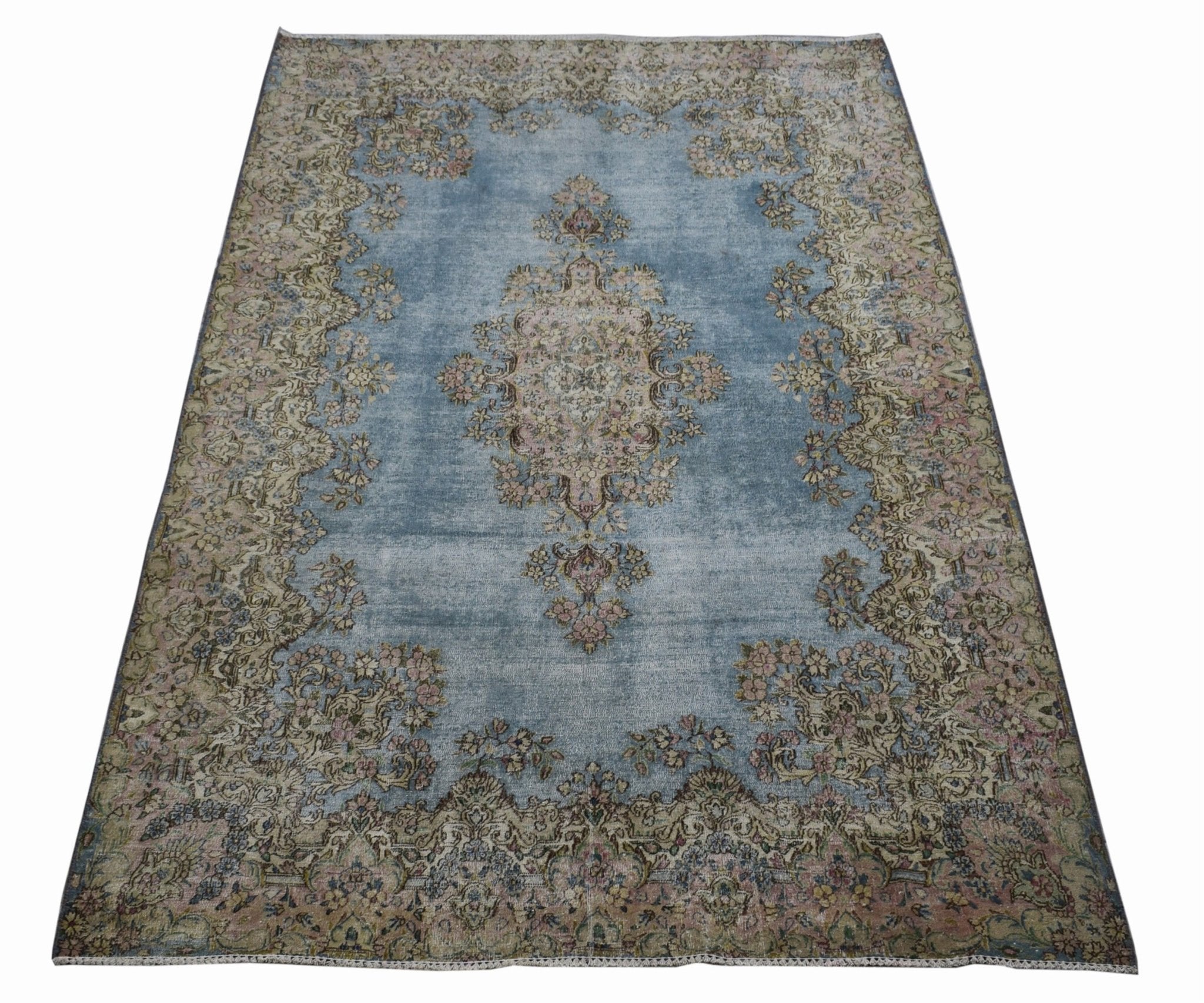 A vintage Persian Kerman rug featuring a central floral medallion on a faded blue field.