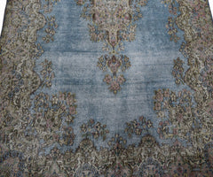 A vintage Persian Kerman rug featuring a blue field with intricate floral patterns and a medallion.