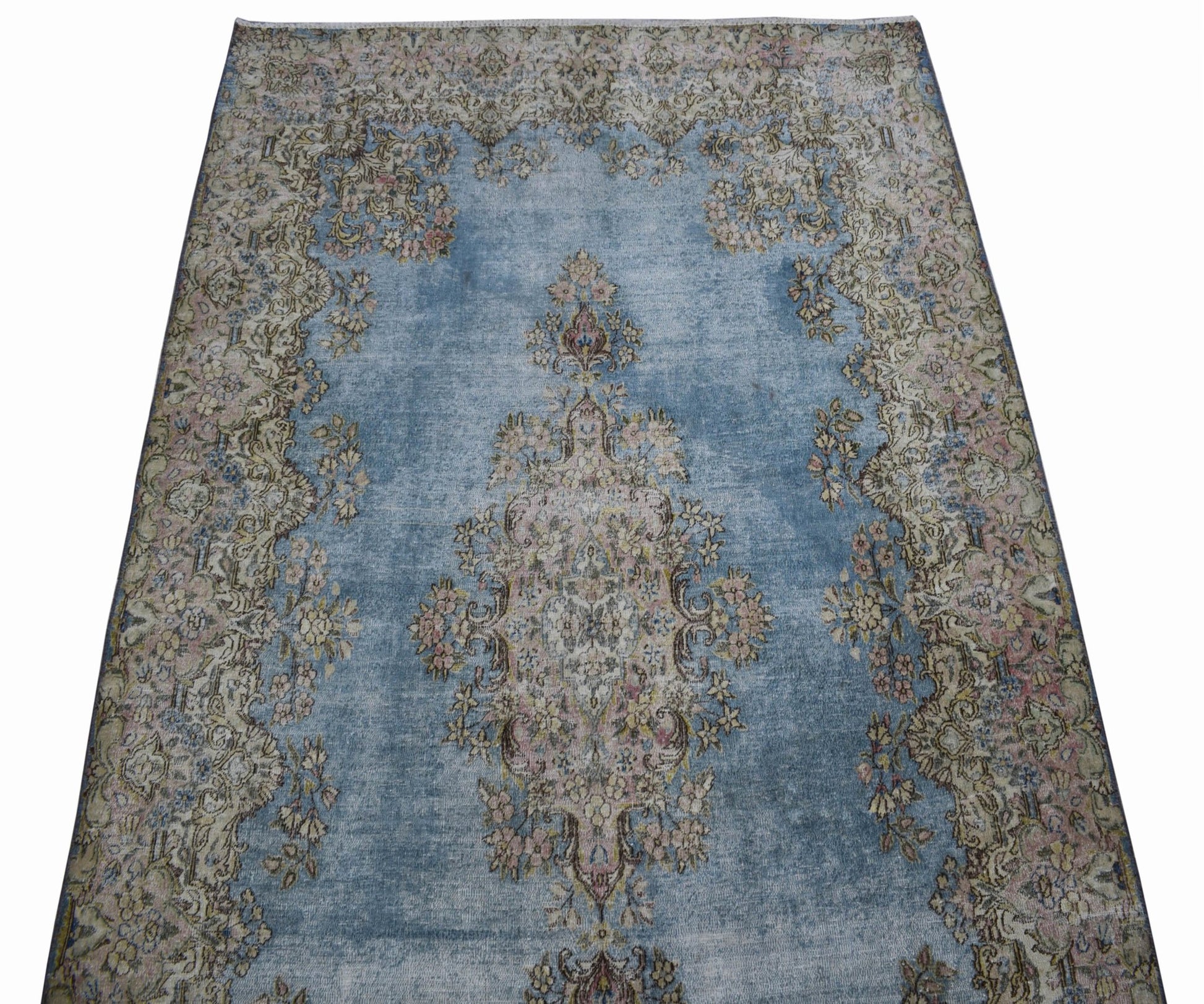 A vintage Persian Kerman rug featuring a central floral medallion on a faded blue field.