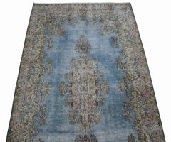 A vintage Persian Kerman rug featuring a central floral medallion on a faded blue field.