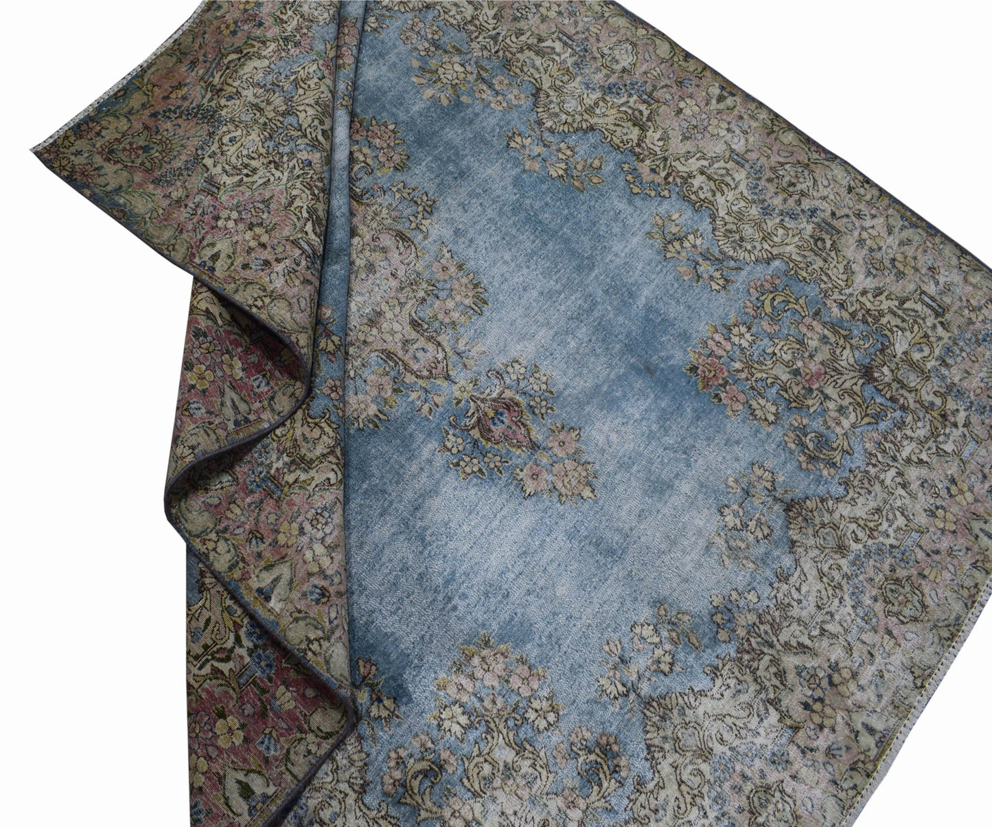 A vintage Persian Kerman rug featuring a faded blue field with intricate floral patterns.