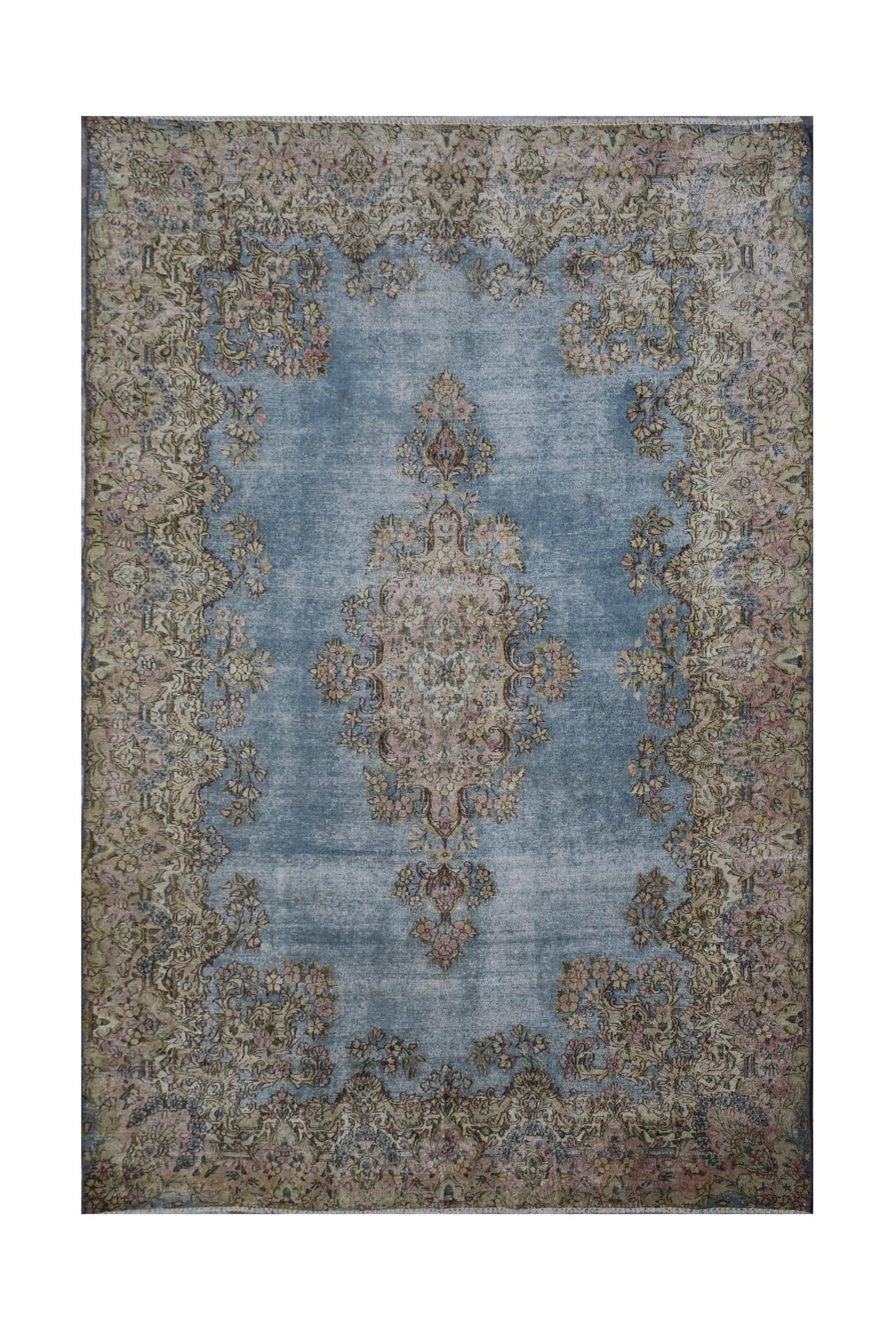 A vintage Persian Kerman rug featuring a central floral medallion on a faded blue field.