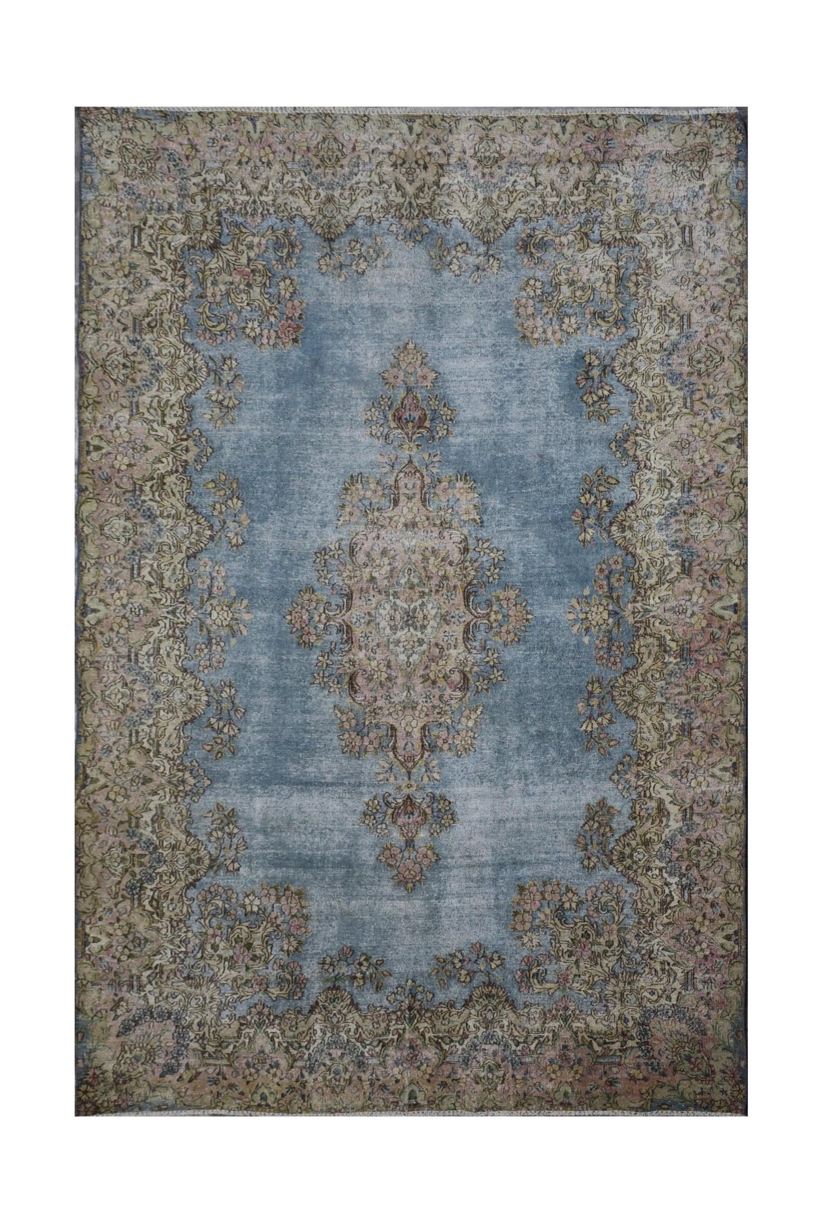 A vintage Persian Kerman rug featuring a central floral medallion on a faded blue field.