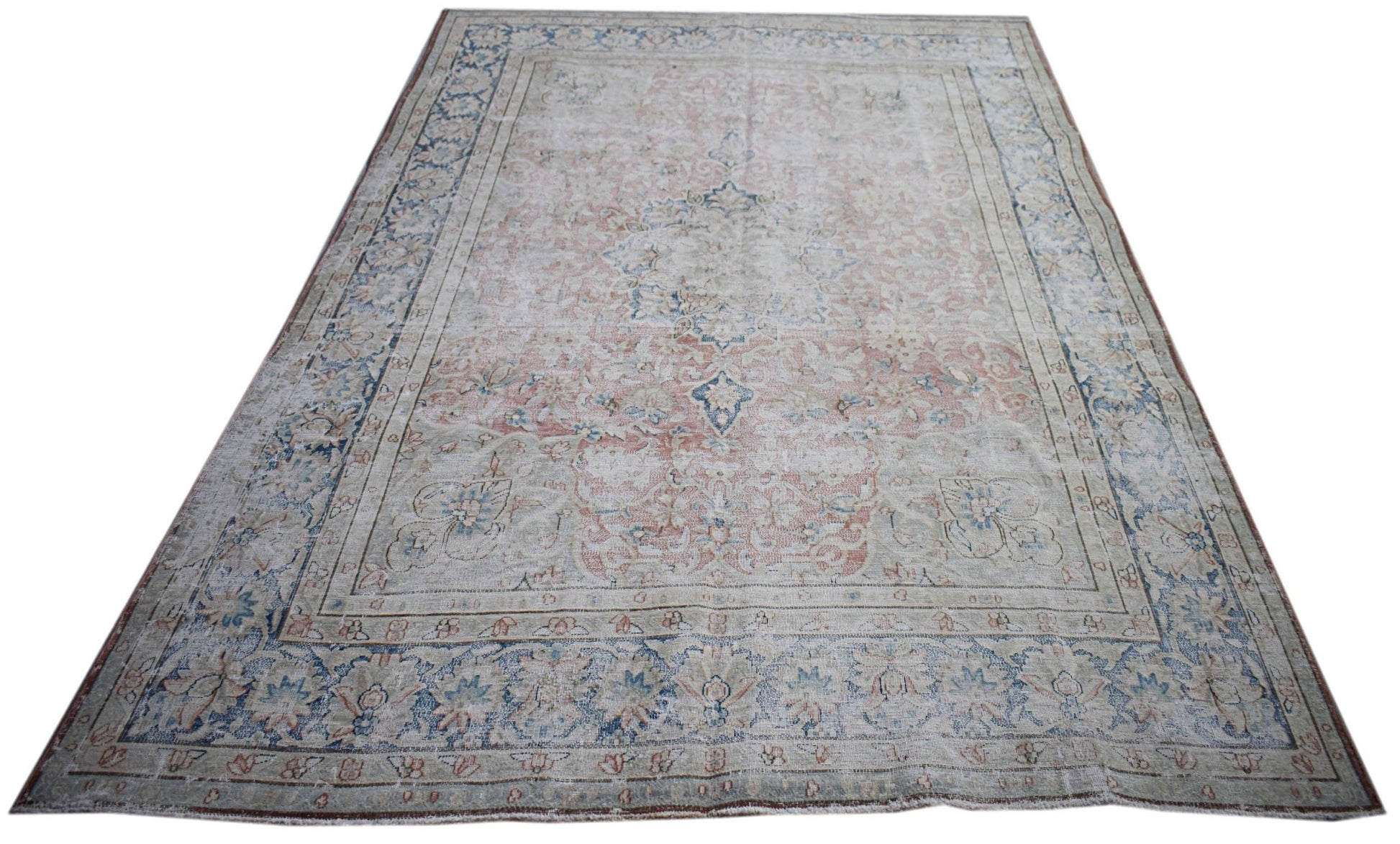 A vintage Persian Kerman rug featuring a central medallion and intricate floral patterns.