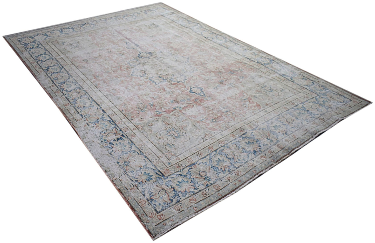A vintage Persian Kerman rug featuring a faded floral medallion design in soft blue and pink tones.