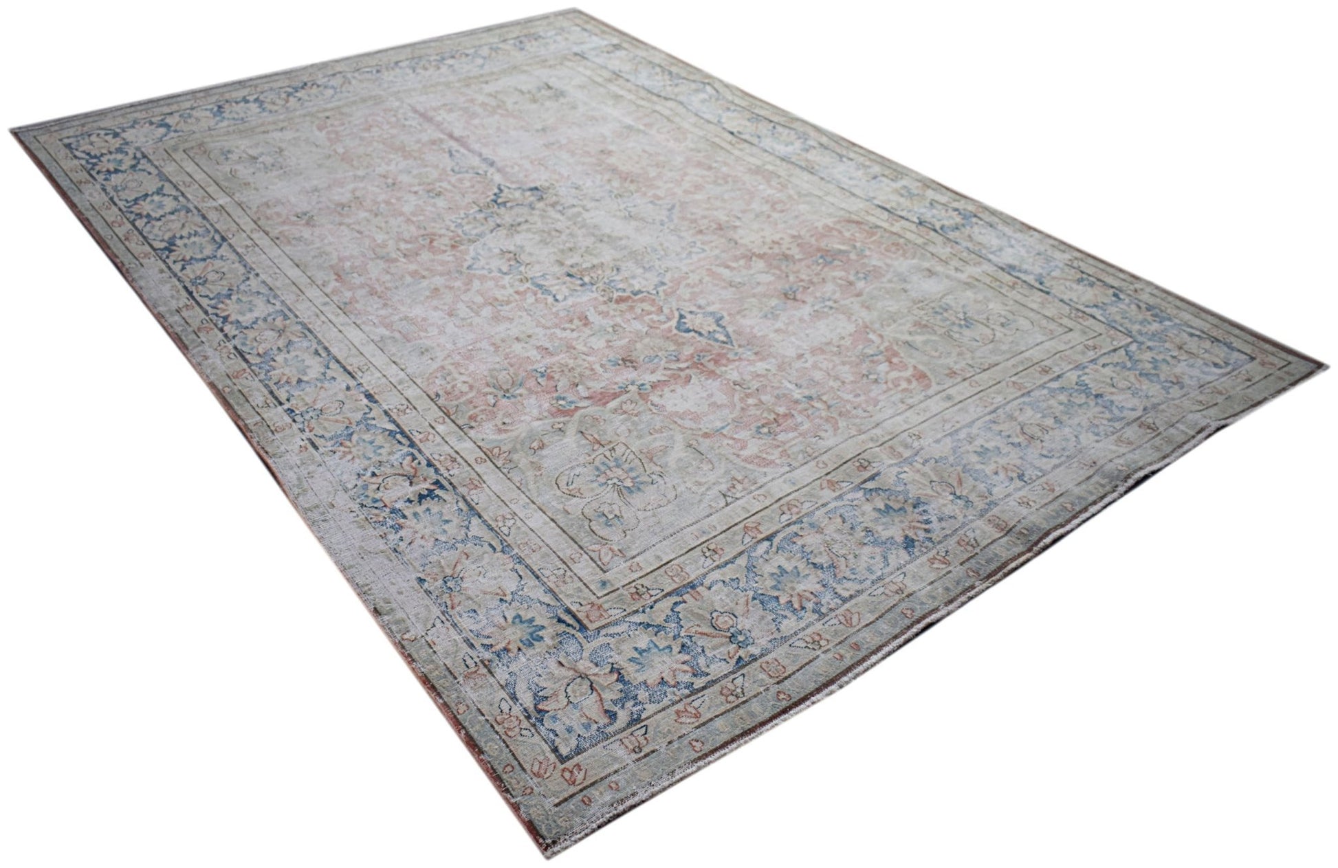 A vintage Persian Kerman rug featuring a faded floral medallion design in soft blue and pink tones.