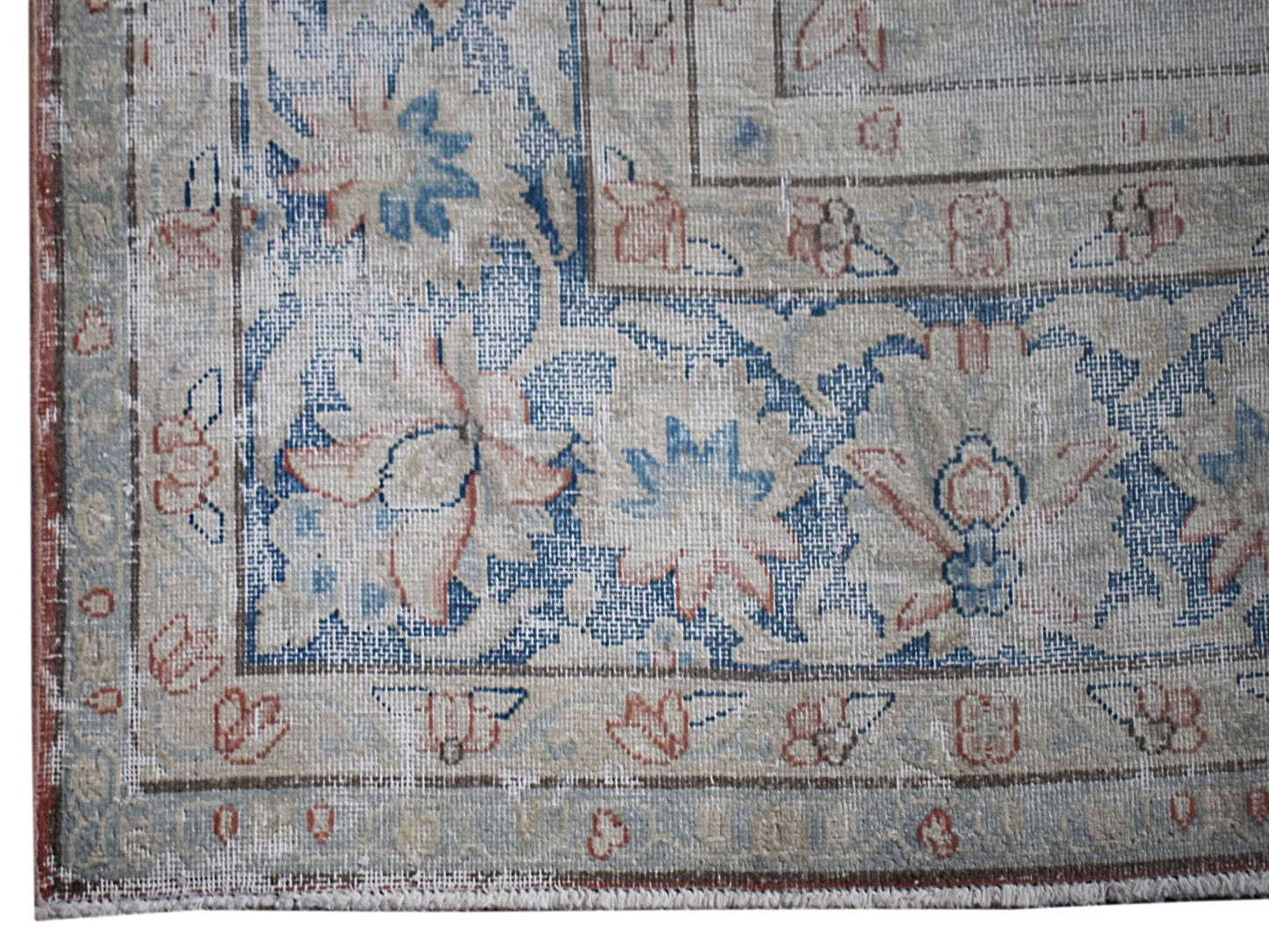 A vintage Persian Kerman rug featuring intricate floral patterns in blue and soft red tones.